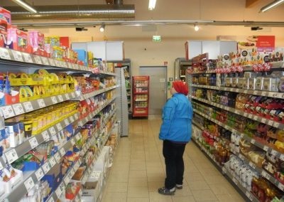Eine Person steht zwischen den Warenreihen eines Supermarktes