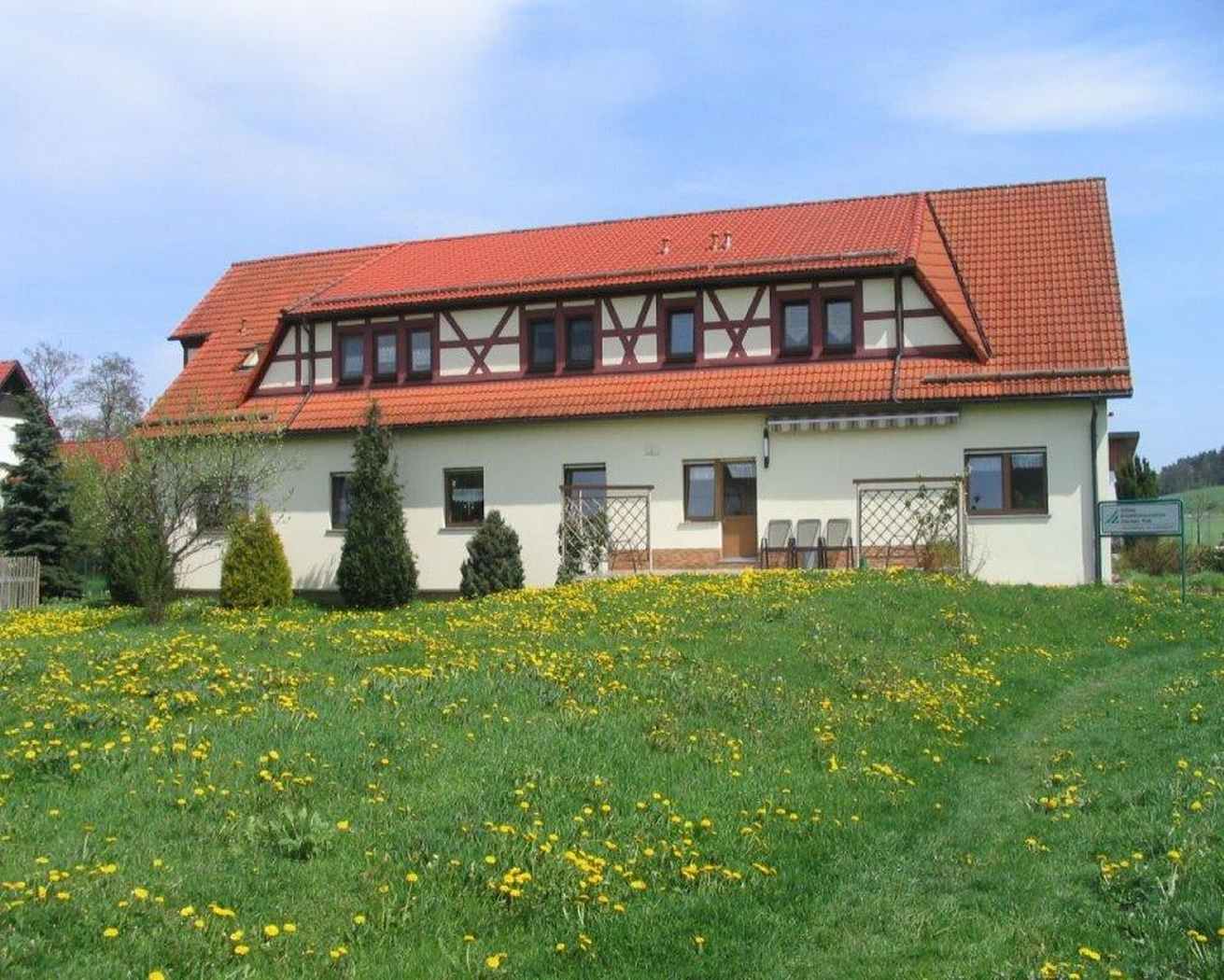 Ein gelbes Haus unter bewölktem, aber blauem Himmel