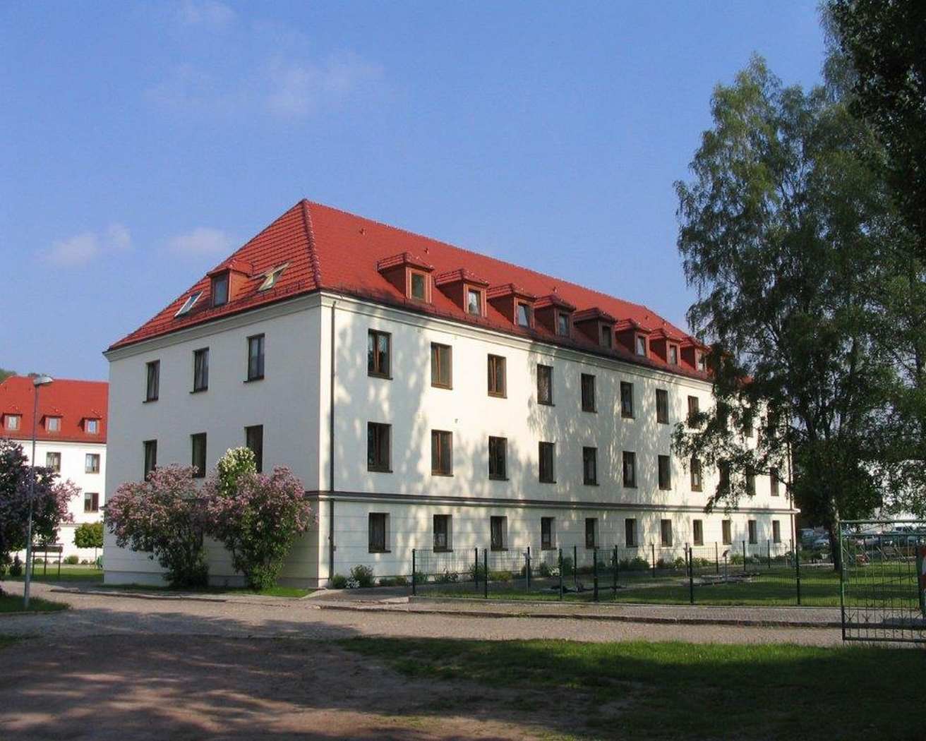 Ein weißes Haus hinter einer grünen Wiese, unter blauem Himmel