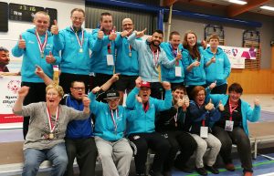 Mehrere Personen in blau-schwarzer Sportkleidung zeigen Daumen nach oben.